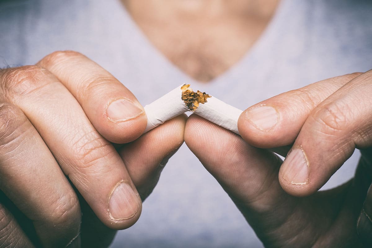 Are smoking and snoring linked? Man breaks cigarette in half.