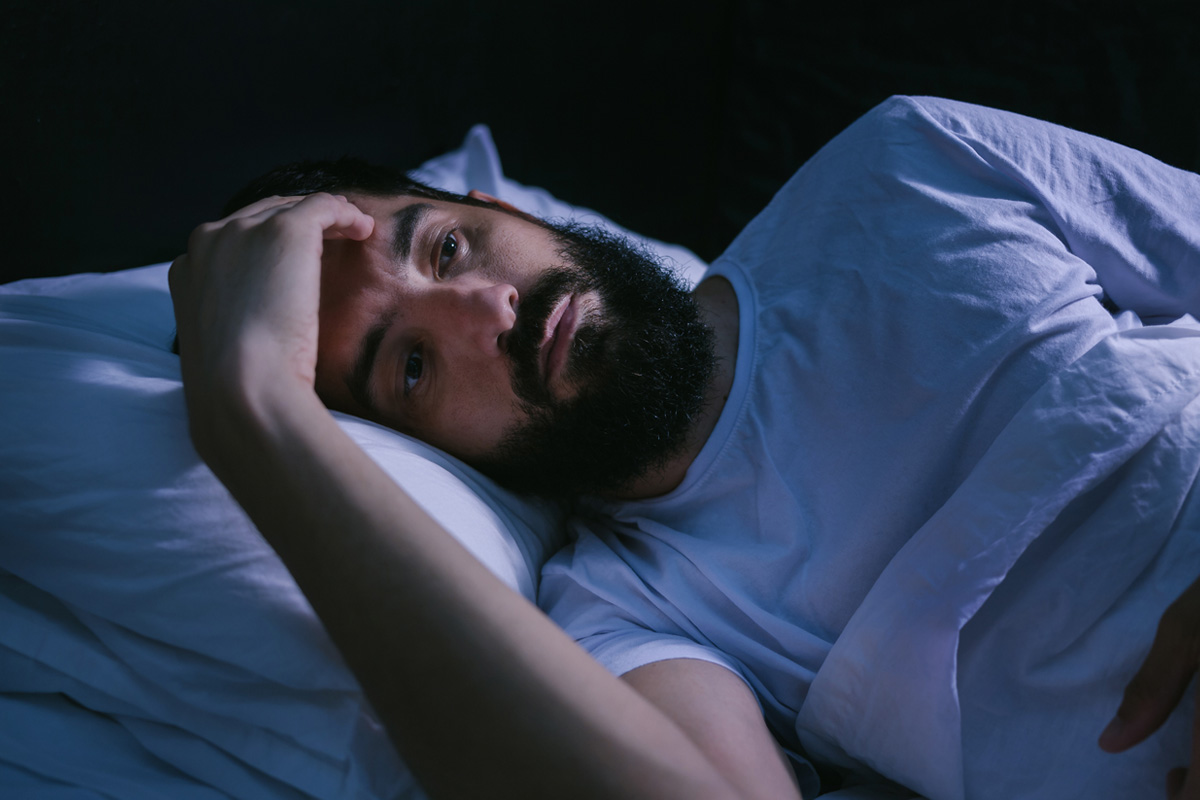 Man in bed late at night, suffering from a sleep disorder.